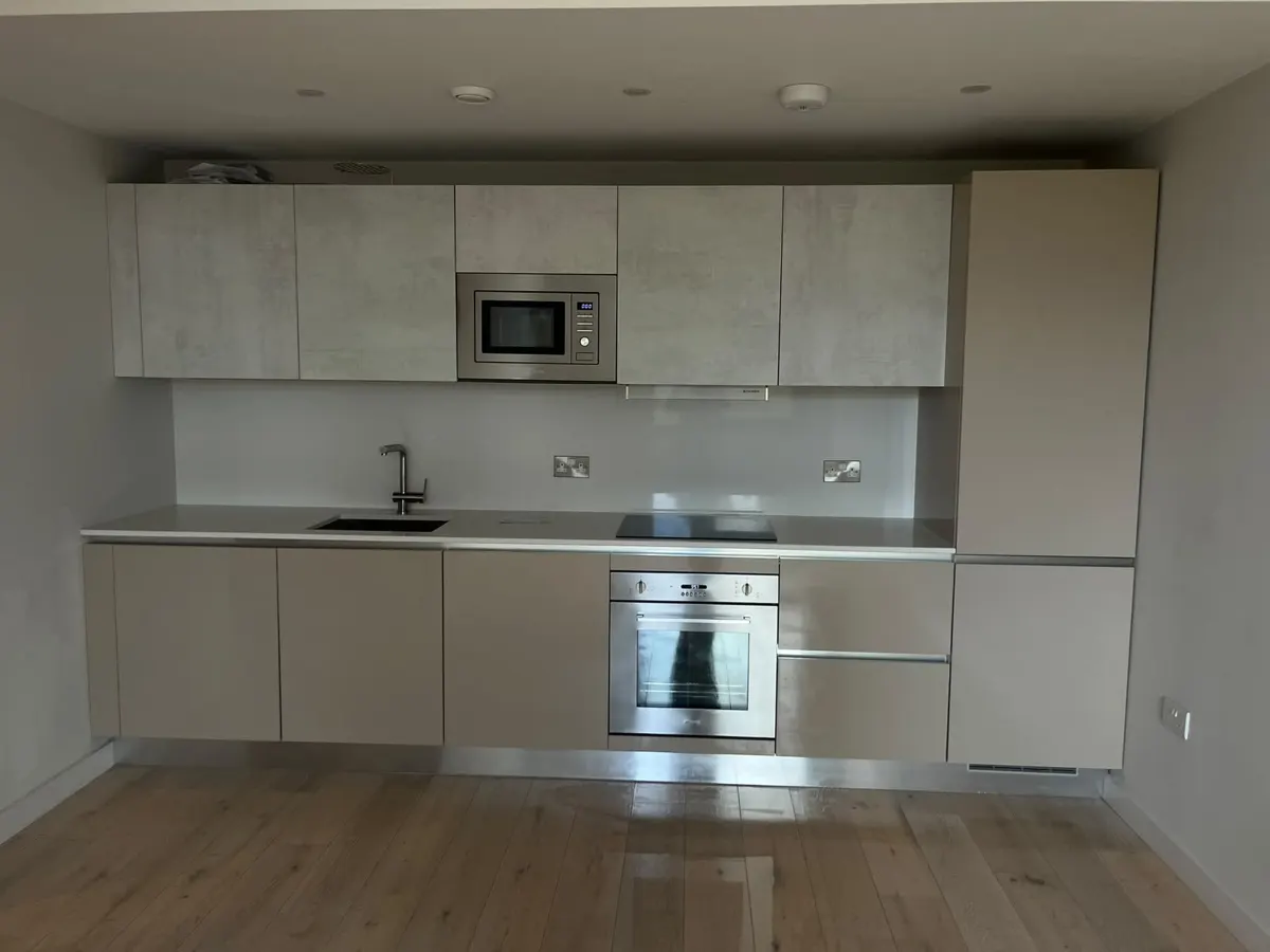 Clean fitted kitchen with built-in oven, microwave and polished wood floor